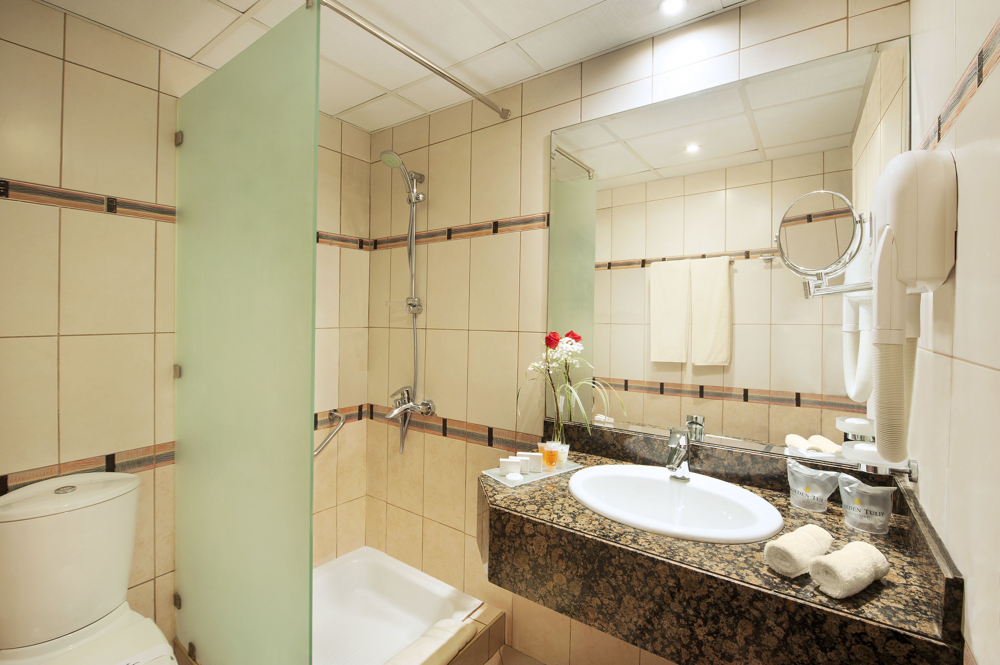 A hotel bathroom with a shower, sink, and toilet.