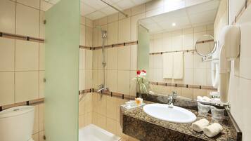 A hotel bathroom with a shower, sink, and toilet.