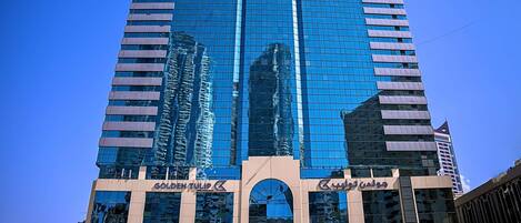 A tall, modern building with reflective glass windows and multiple commercial signs.