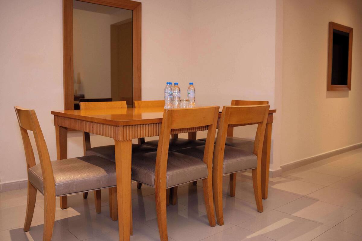 A dining area with a wooden table and chairs, a mirror on the wall, and water bottles on the table.
