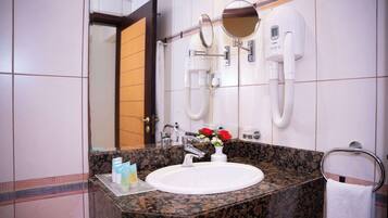 Une salle de bain avec un lavabo blanc, un miroir, un porte-serviettes et une pomme de douche.