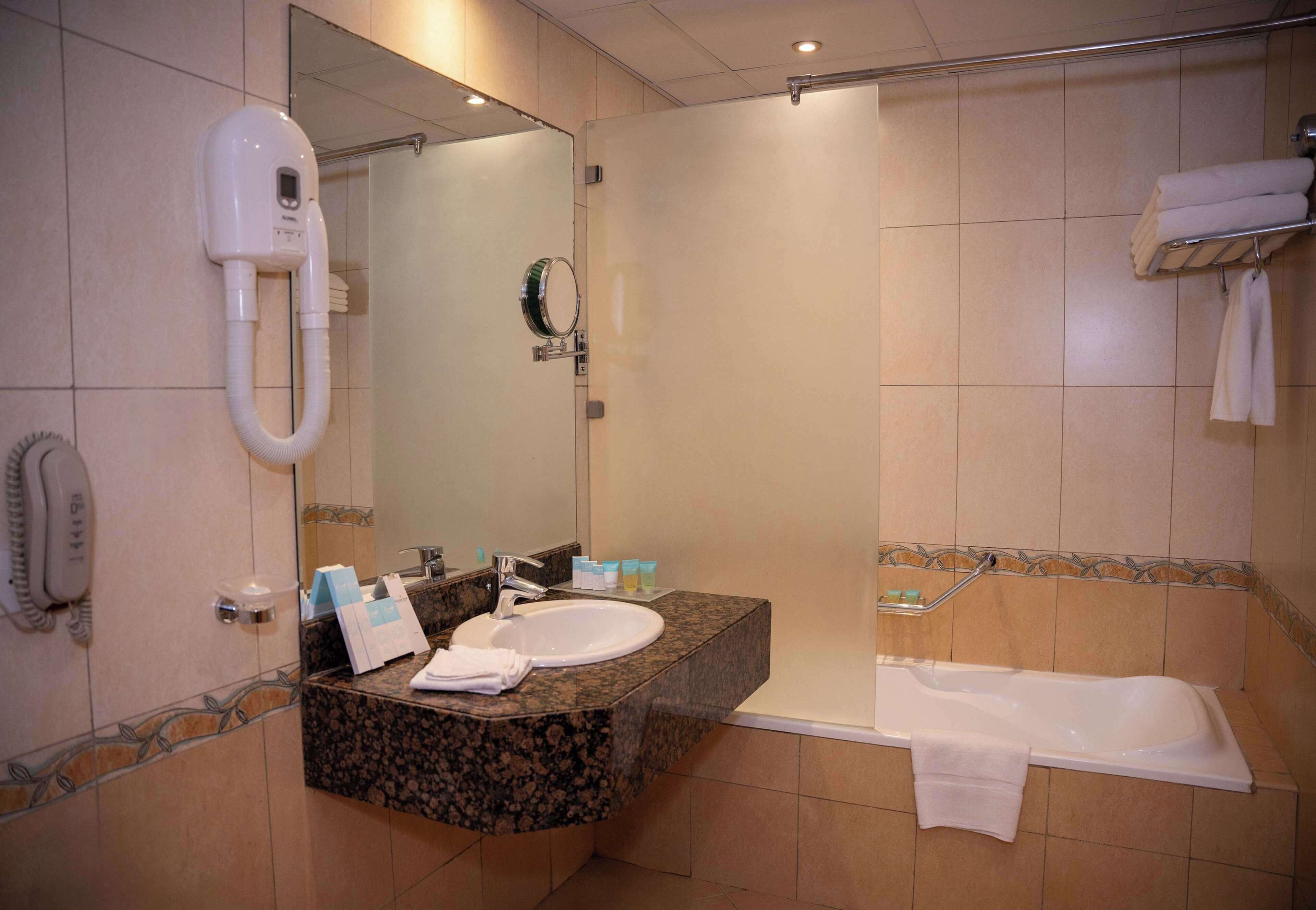 Un baño con lavamanos, espejo, secador de pelo y bañera.