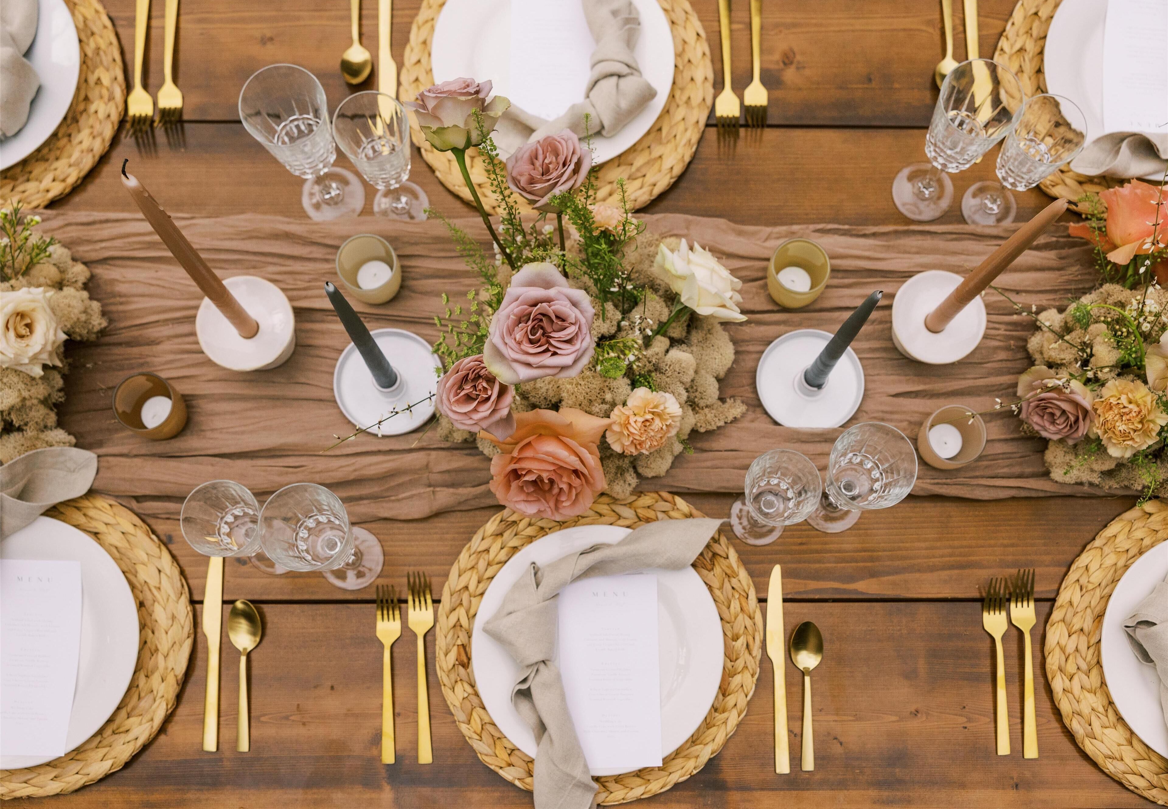A table set for a meal with plates, cutlery, glasses, and a centerpiece of flowers.