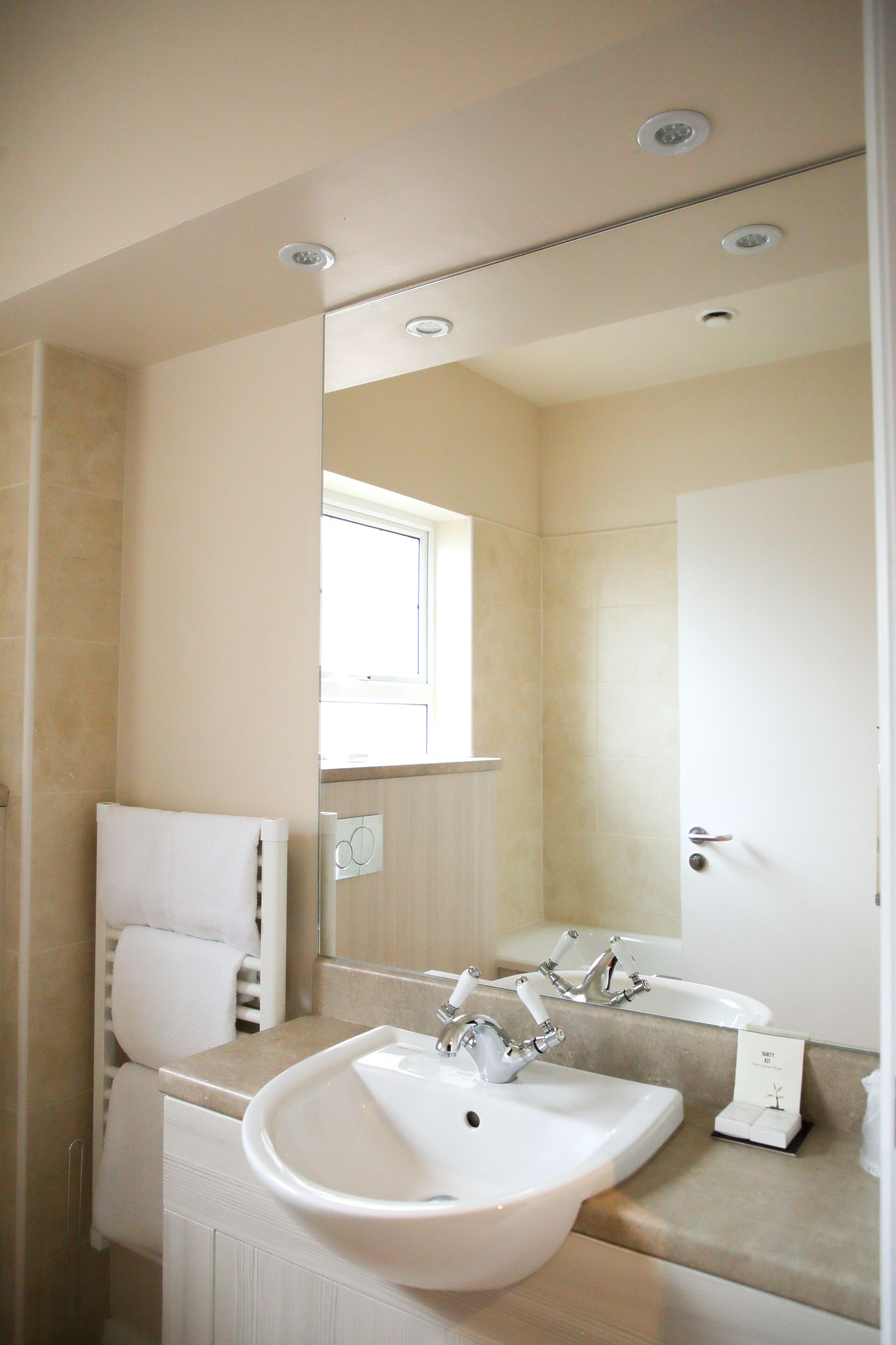 A bathroom with a white sink, a mirror, and a towel rack.