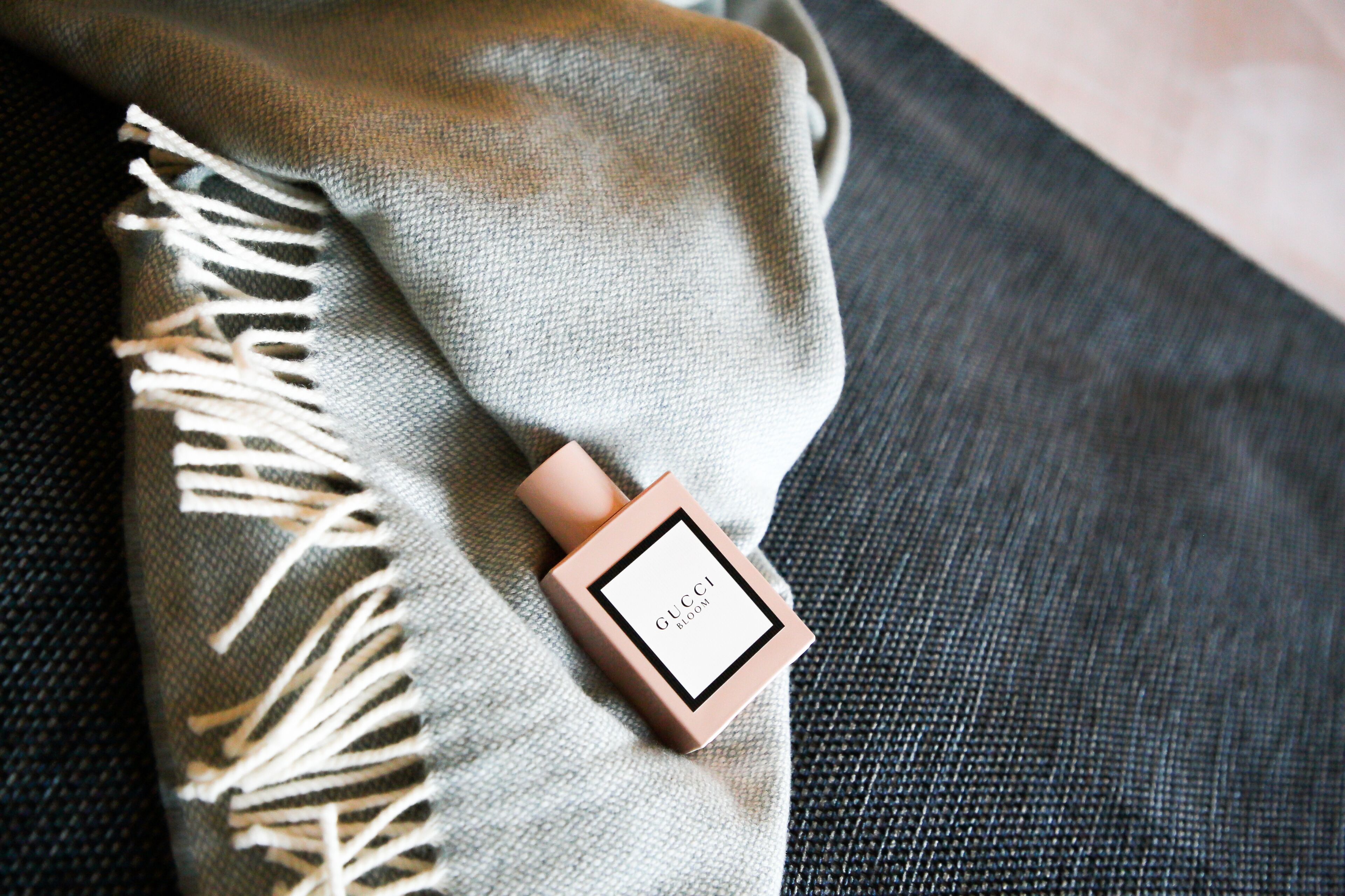 A Gucci perfume bottle on a textured fabric surface.