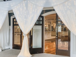 Entrada de hotel con cortinas blancas y puerta de cristal que da a un interior bien iluminado.
