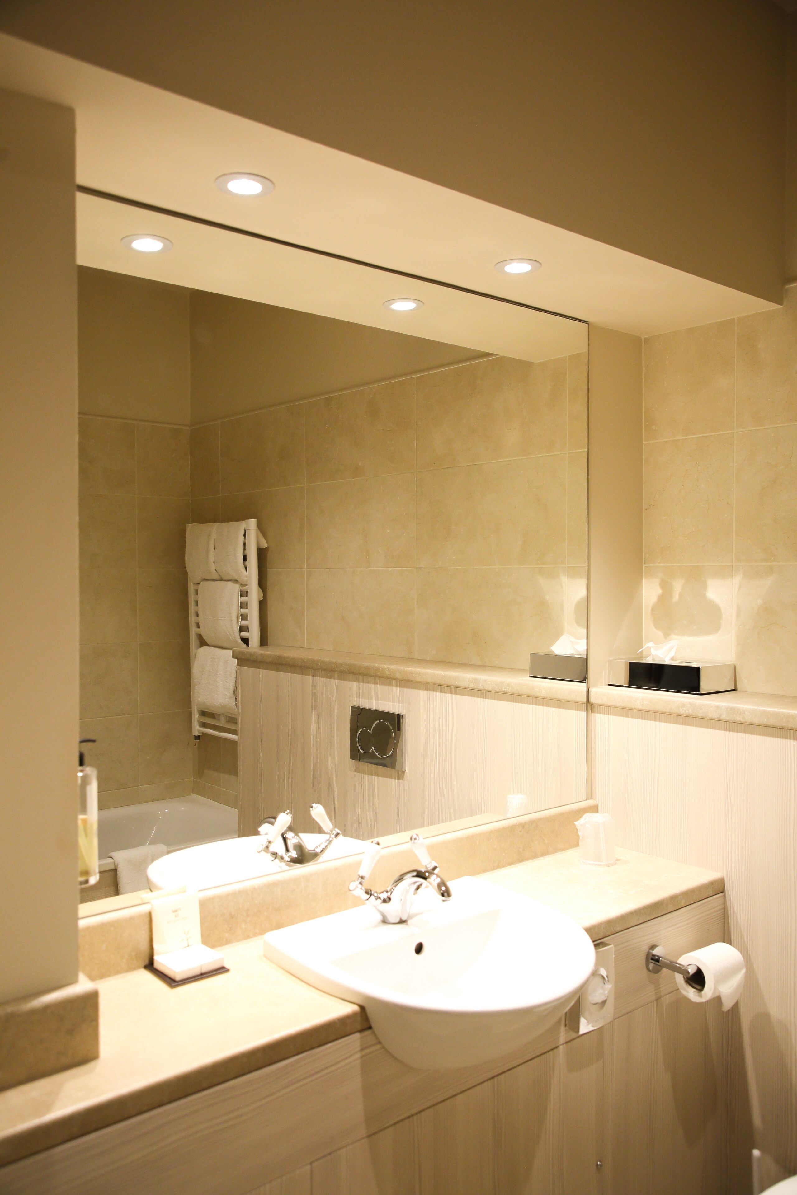 Un baño moderno con lavamanos doble, espejo, toallero y dispensador de papel higiénico.