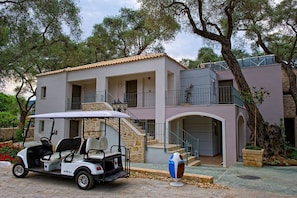 A two-story building with a stone facade, a balcony, and a golf cart parked in front. - Parga Beach Resort (Parga)