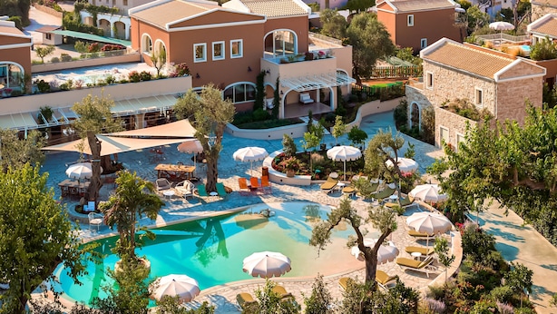A resort with a swimming pool, lounge chairs, and a view of the sea and boats. - Parga Beach Resort (Parga)