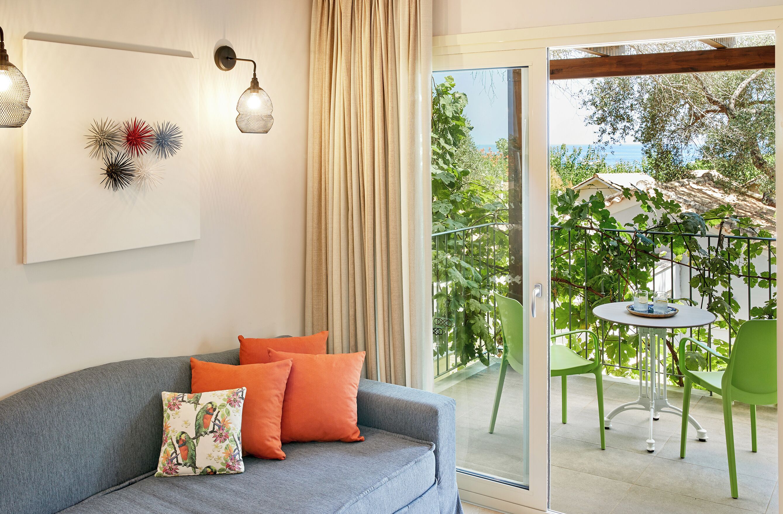 A modern living room with a grey sofa, orange cushions, and a wall-mounted abstract art piece.