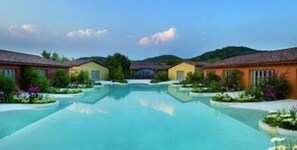A resort with a central swimming pool, multiple guest villas, and lush landscaping. - Joia Luxury Hotel & Luxury Apartments (Brusaporto)