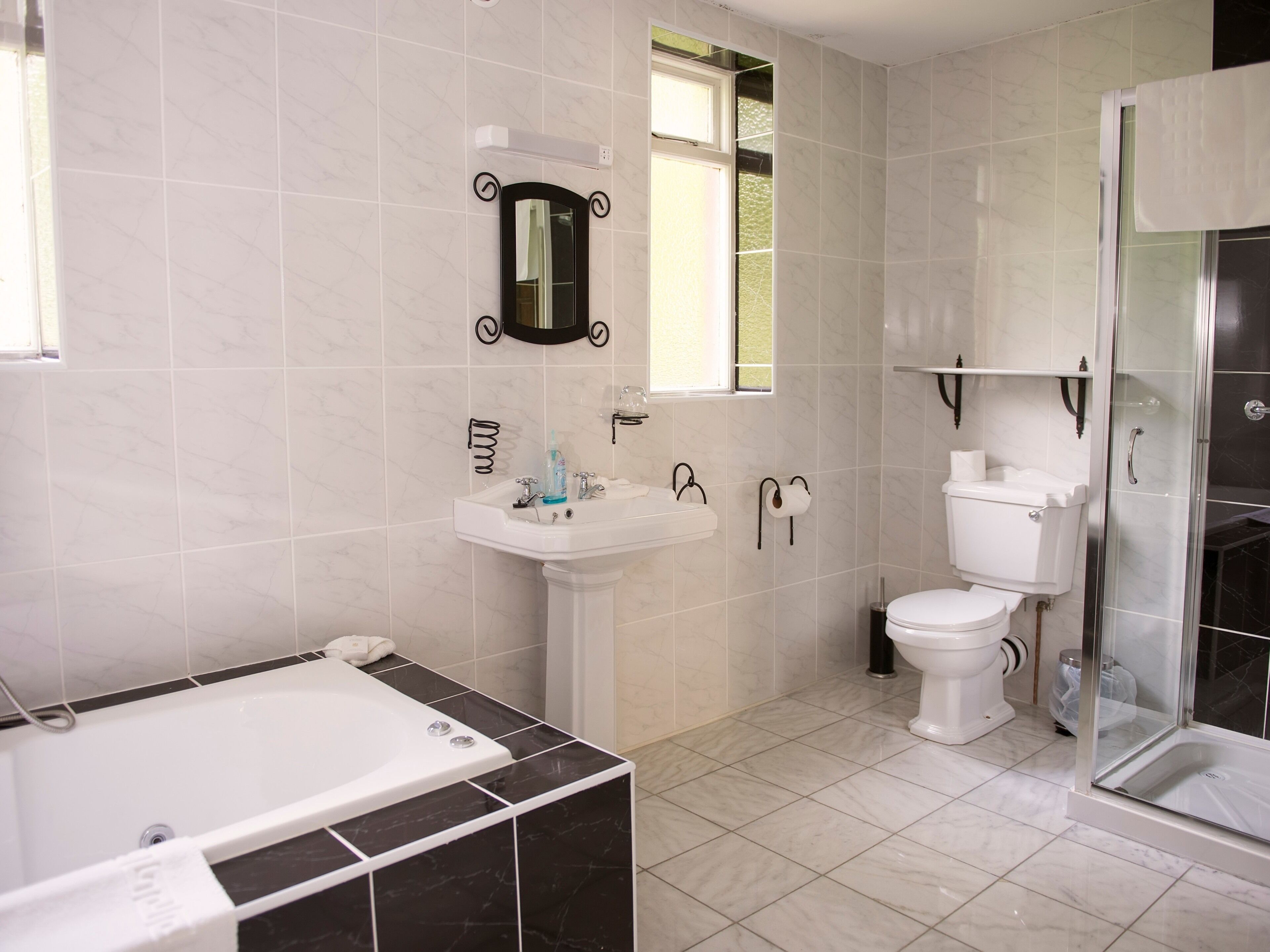 A modern bathroom with a bathtub, sink, toilet, and glass shower enclosure.