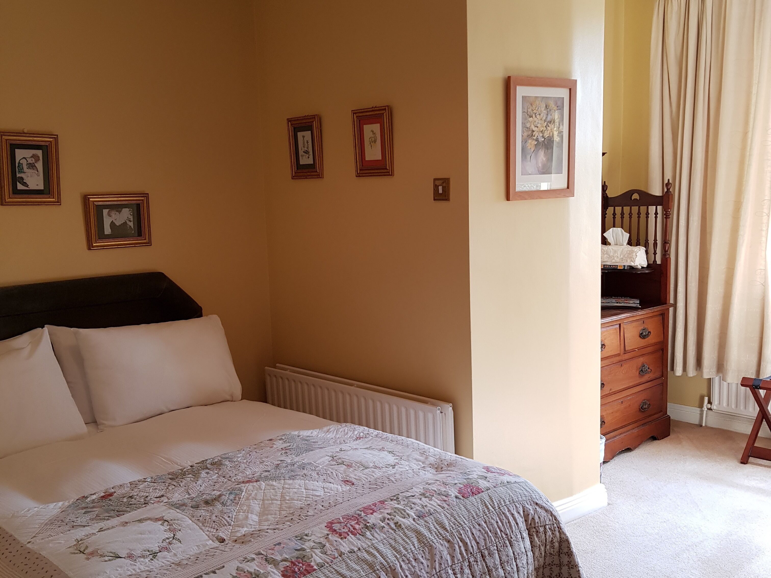 Un dormitorio con cama, cómoda y radiador.