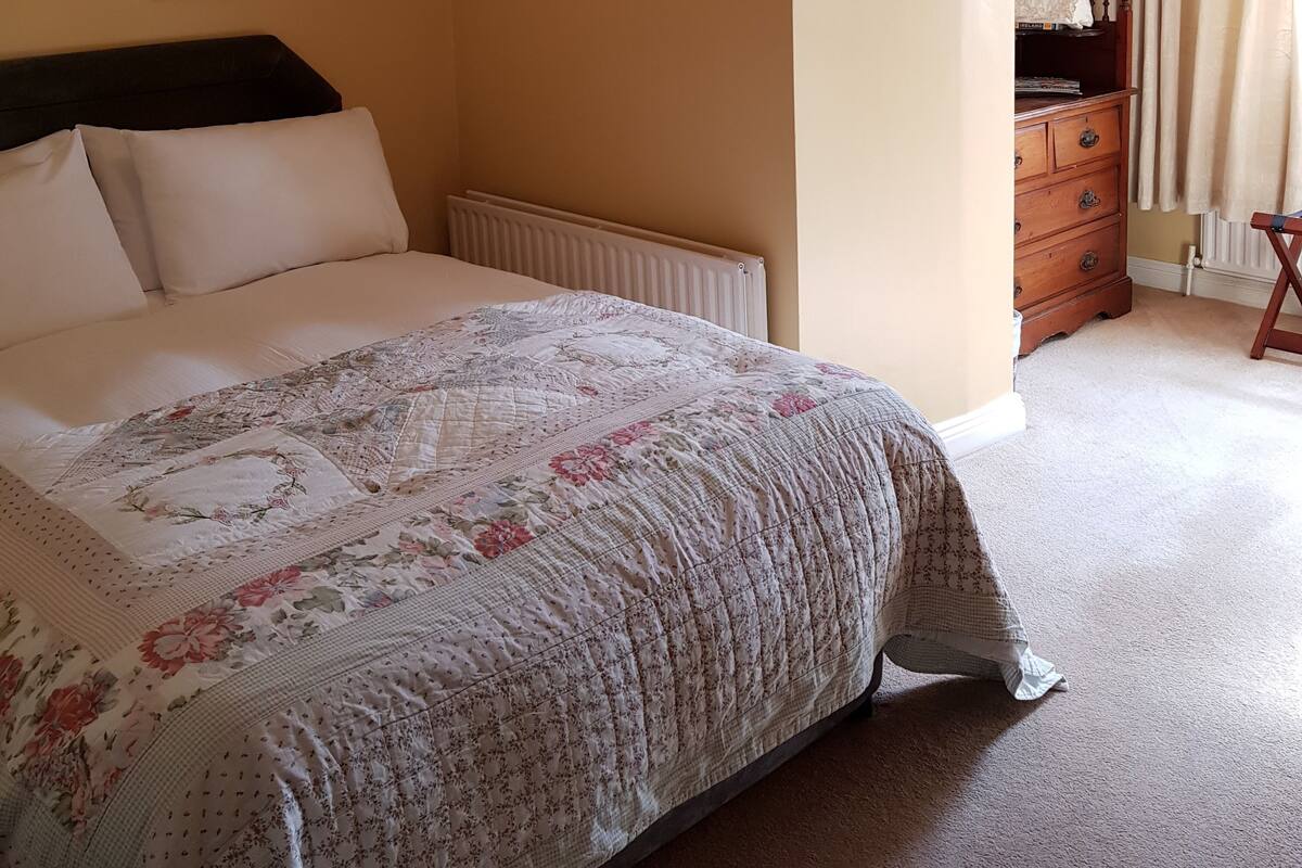 A bedroom with a bed, a dresser, and a radiator.