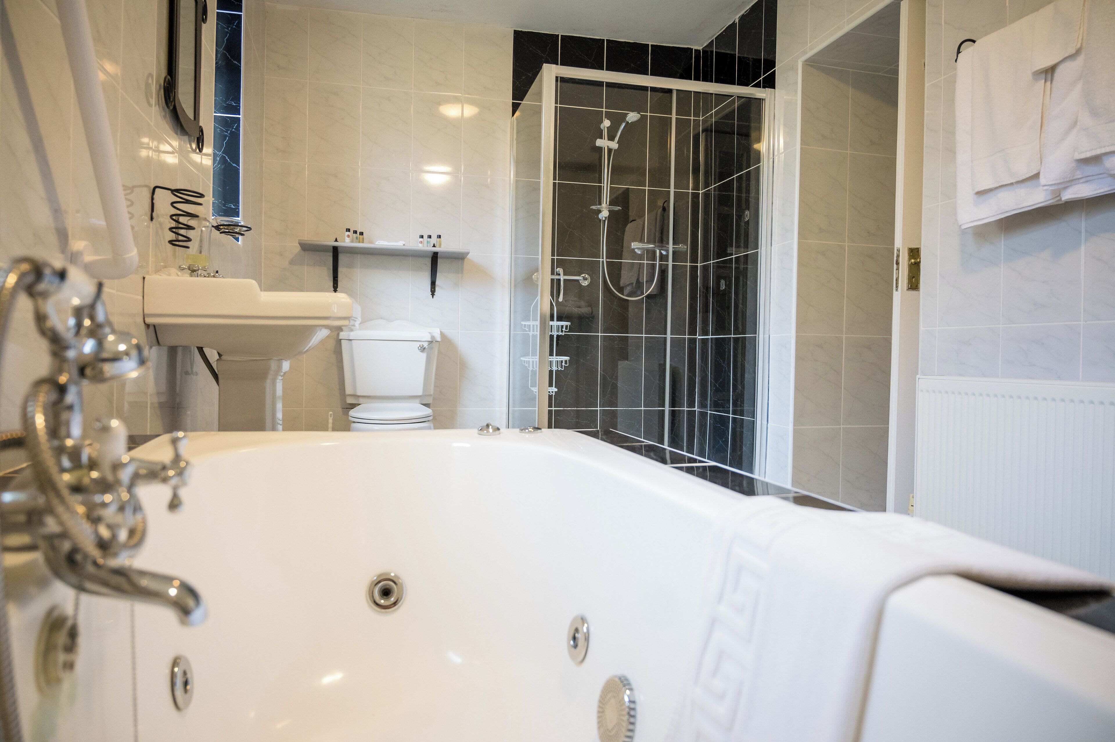 Un baño moderno con una bañera grande, una ducha con mampara de vidrio y un inodoro.