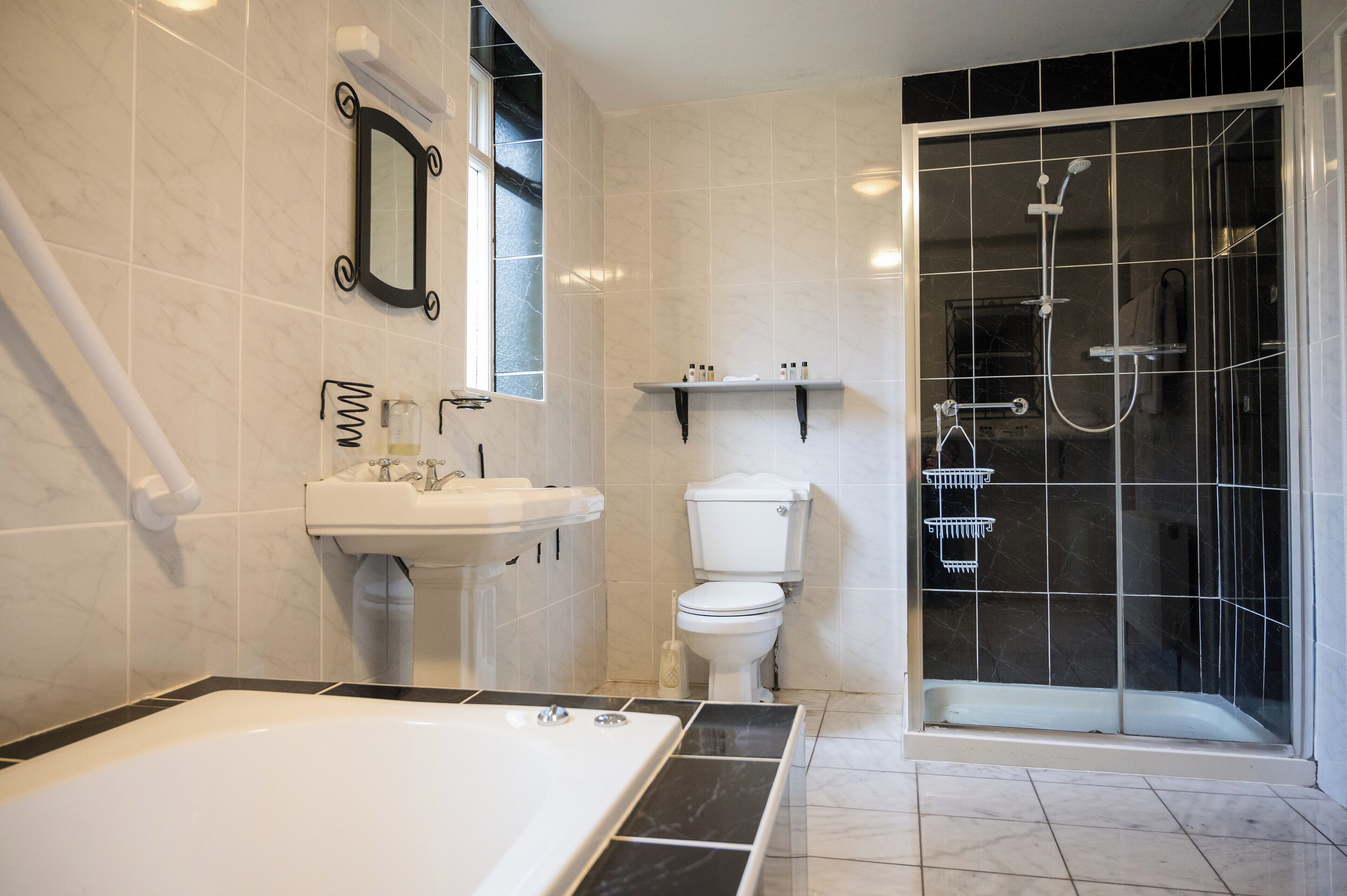 Une salle de bain moderne équipée d’une baignoire, d’un lavabo, de toilettes et d’une douche séparée par une paroi en verre.