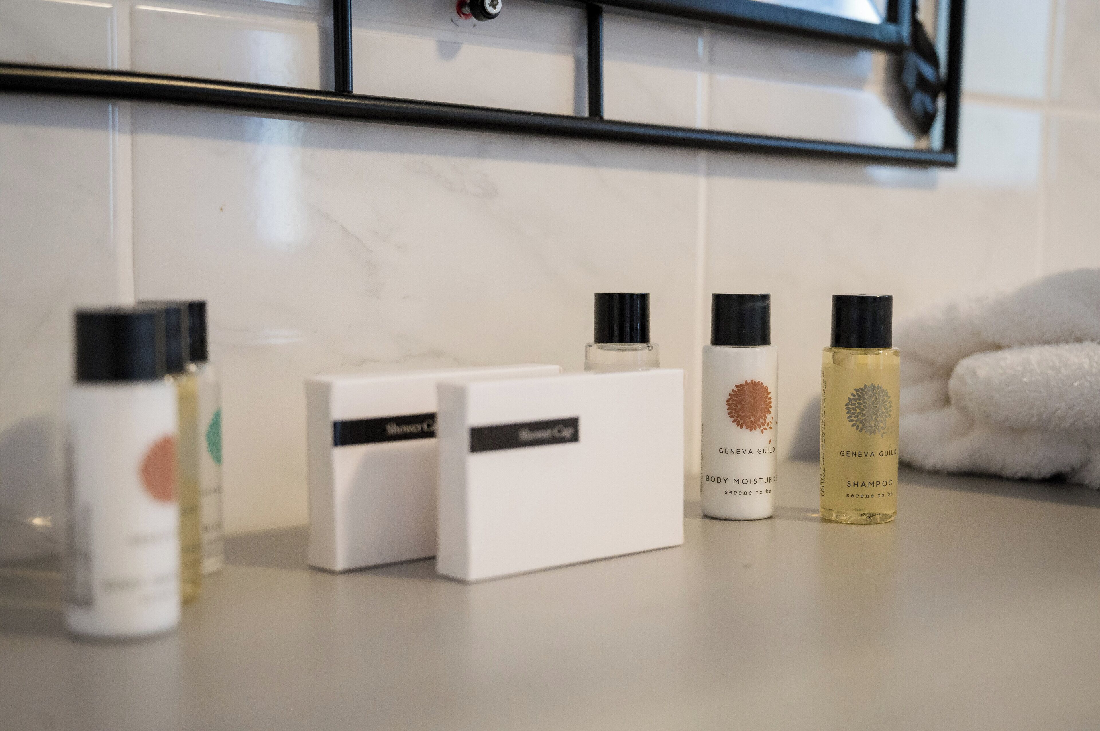 A bathroom counter with various toiletries including a shower cap, body lotion, and shampoo.