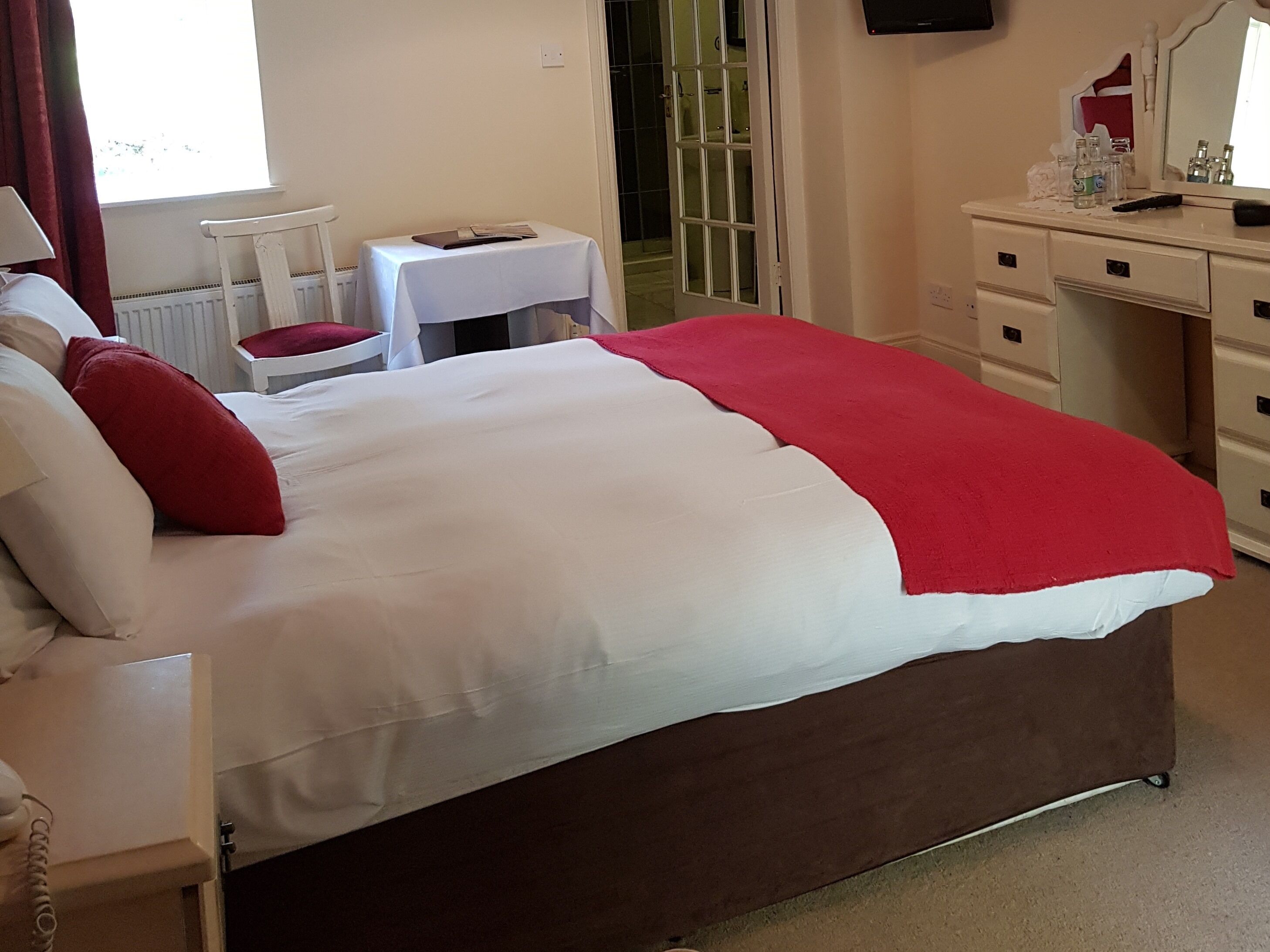 A hotel room with a bed, a desk, a chair, and a dresser.