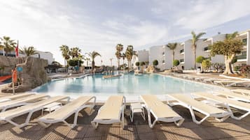 Un área de piscina con sillas de descanso y palmeras.