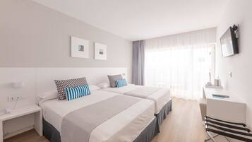 Habitación de hotel con dos camas, un escritorio, una silla y un televisor montado en la pared.