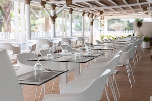 A covered outdoor dining area with white tables and chairs, arranged in rows. - BLUESEA Costa Bastian (Teguise)