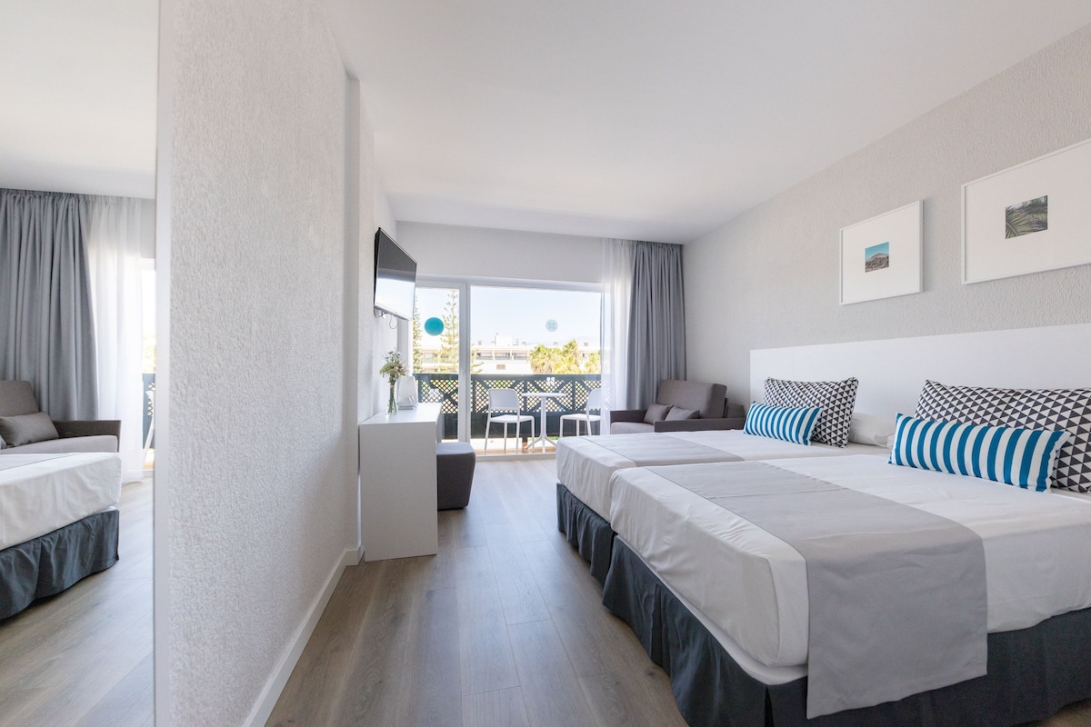 A hotel room with two beds, a balcony, and a view of the city.