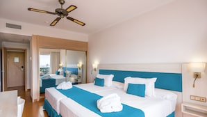 Habitación de hotel con una cama grande, ventilador de techo, baño y vista al mar.