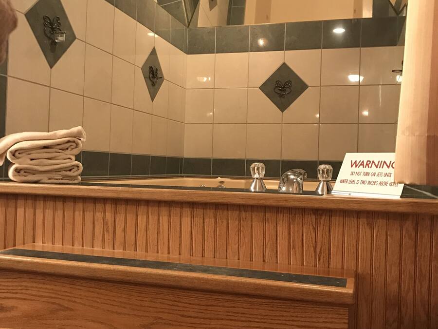 A hotel reception area with a wooden counter, a stack of towels, a warning sign about the water level, and a tiled wall with diamond patterns.