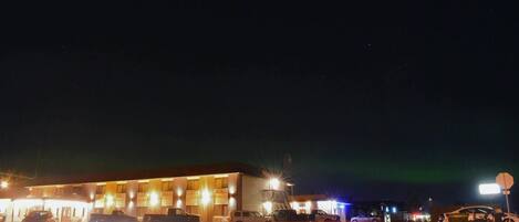 Un motel con varias habitaciones, un estacionamiento y una calle con coches.