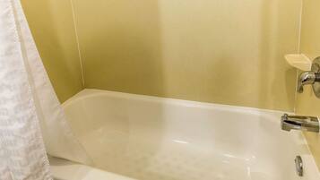 A bathtub with a chrome faucet, a white towel, and a soap dish on the wall.