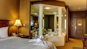Une chambre d’hôtel avec un grand lit, une lampe de chevet, un téléphone, un miroir et une salle de bain équipée d’un lavabo et d’un porte-serviettes.