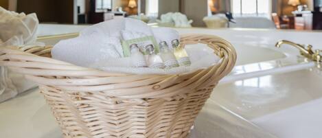 A wicker basket with a white towel and toiletries on a bathroom counter.
