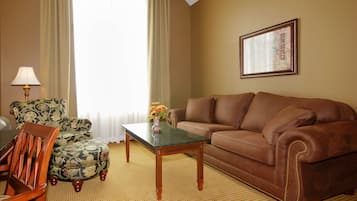 A living room with a brown leather sofa, a floral armchair, a wooden coffee table, and a lamp.
