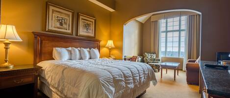 A hotel room with a large bed, two bedside lamps, a small table, a chair, and a TV.