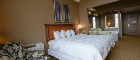 A hotel room with a large bed, a sofa, a desk, and a bathroom.