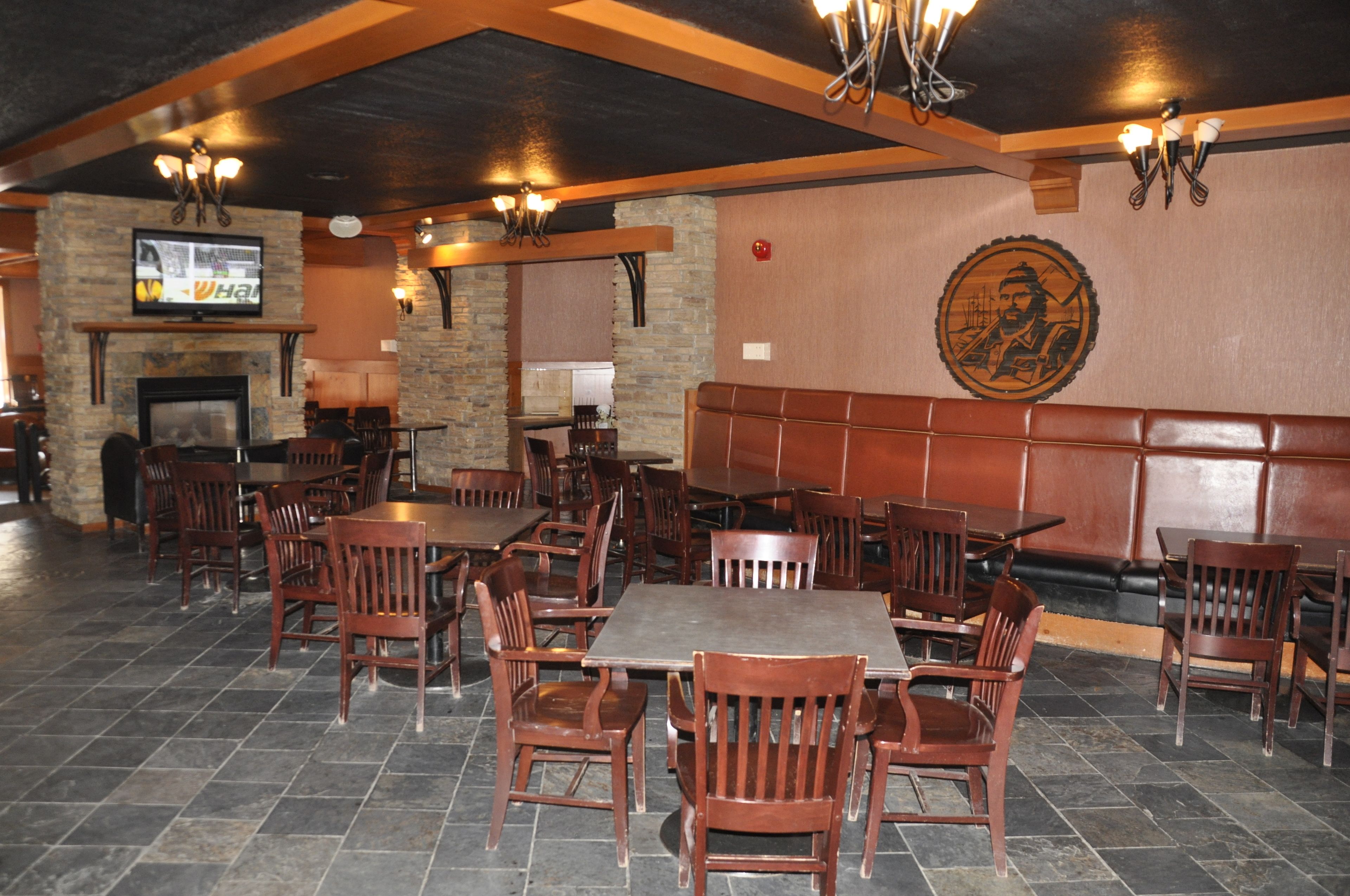 Un restaurante con mesas y sillas de madera, paredes de piedra y una chimenea.