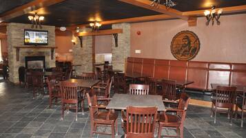 Un restaurante con mesas y sillas de madera, paredes de piedra y una chimenea.