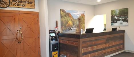A reception desk with a wooden counter, an ATM, and a sign for Woodcutter Lounge.