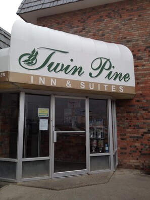 A Twin Pine Inn & Suites with a brick facade and a large sign above the entrance. - Twin Pine Inn & Suites (Hinton)