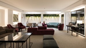 En moderne stue med en modulsofa, røde lænestole, et sofabord i glas og en grøn sofa.