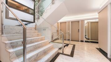 A hotel lobby with marble stairs, a glass railing, and a modern design.