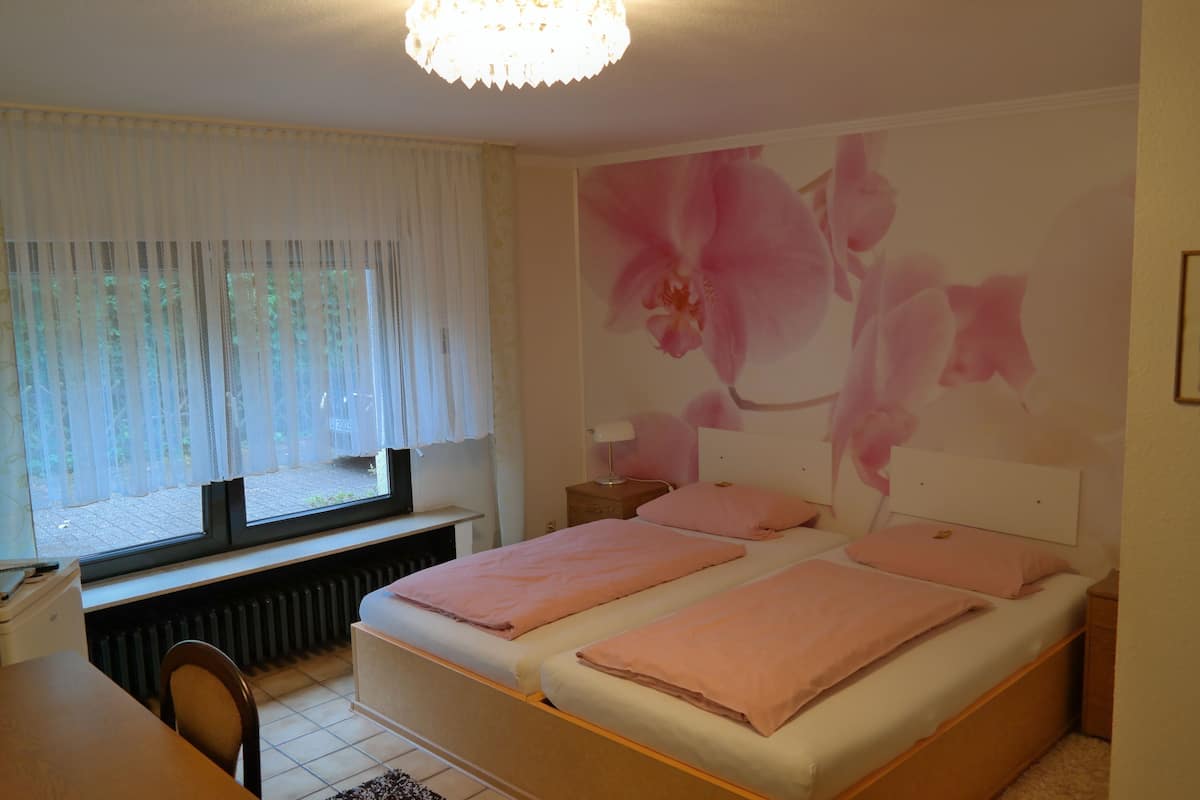 A bedroom with two beds, a desk, and a window with curtains.