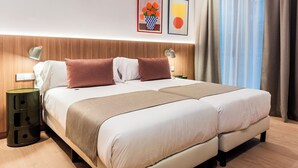 A double bed with a wooden headboard, two bedside tables with lamps, a nightstand, and a wall-mounted light. - Hotel California (Barcelona)