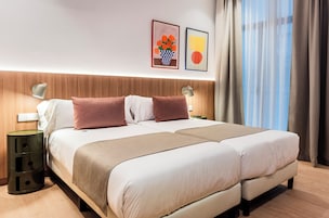 A double bed with a wooden headboard, two bedside tables with lamps, a nightstand, and a wall-mounted light.