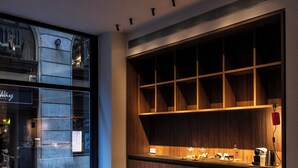 A modern kitchen with a built-in island, wooden cabinets, and a dining area with a large table and blue chairs. - Hotel California (Barcelona)