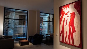 A modern living room with a large abstract painting, a sofa, and a coffee table. - Hotel California (Barcelona)