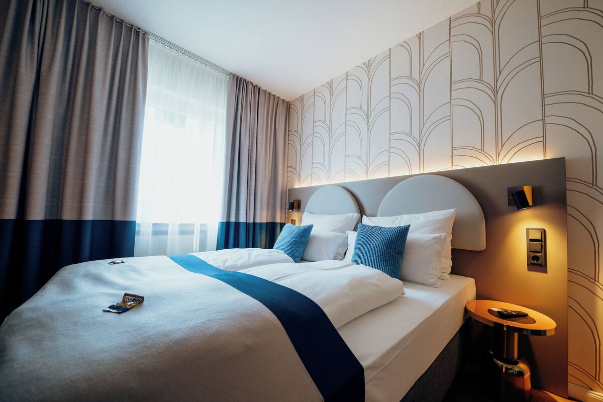 Een hotelkamer met een groot bed, nachtkastje en een wandlamp.