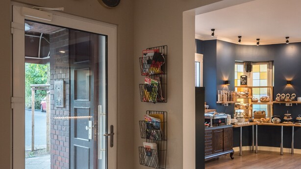 A modern kitchen with wooden flooring, a built-in oven, and a countertop with various kitchen items. - guestified. BARBAROSSA Hotel (Ratingen)