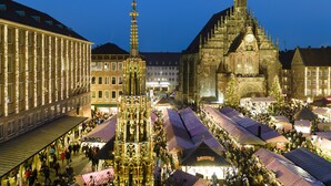 A historic building with a clock tower, surrounded by market stalls and festive lights. - Hotel Metropol Nürnberg (Nuremberg)