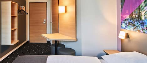 Une chambre d’hôtel comprenant un lit, un bureau, une chaise, une armoire et un miroir.